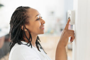 Woman setting thermostat.