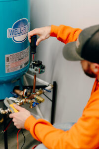 Summers PHC technician adjusting the pressure switch on a Well-Rite pressure tank during a well maintenance service in Huntington, Indiana