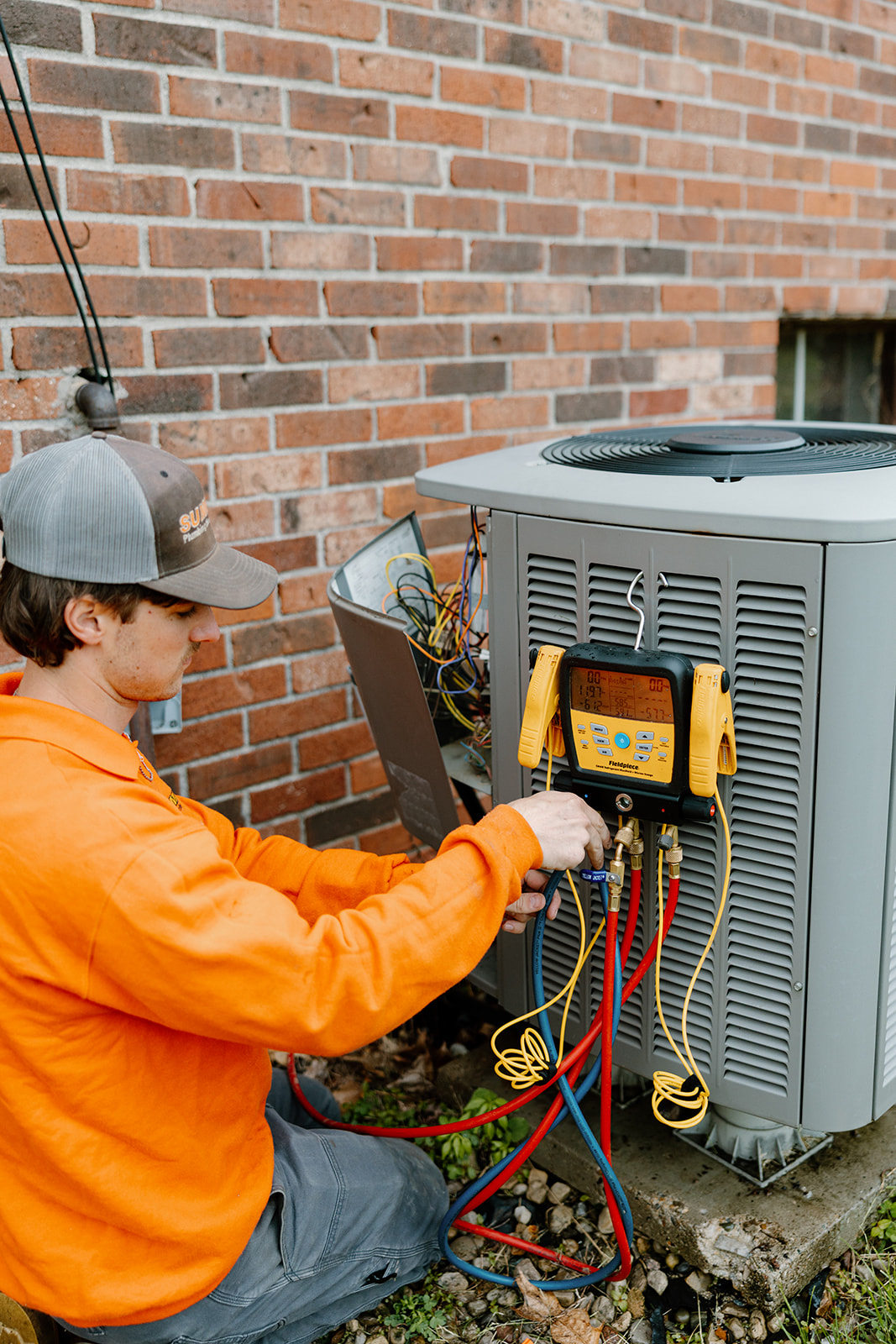 Summers PHC technician using digital manifold gauges to check air conditioner refrigerant levels during an AC repair