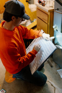 Summers Plumbing technician inspecting a new 18x20x1 pleated AC filter before installation in a Kokomo, IN home