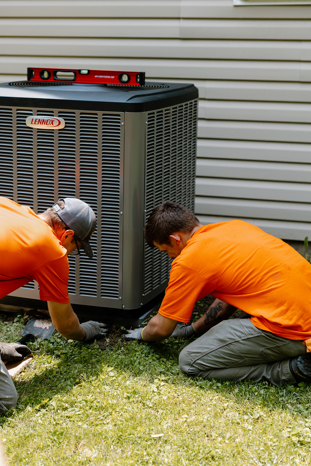 Two Summers PHC technicians installing and leveling a new Lennox AC condenser unit at a Kokomo, Indiana home