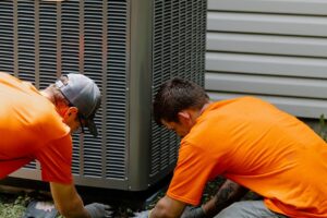 Two Summers technicians leveling a new outdoor unit beside a Kokomo home