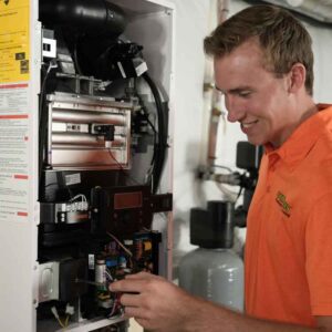 Summers plumber in an orange shirt working on a gas water heater