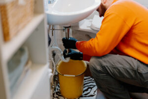 Summers Plumbing technician inspecting a clogged bathroom sink drain in a Marion, IN home