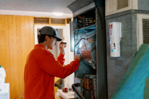 Summers Plumbing Heating and Cooling technician inspecting an indoor AC unit with a flashlight during an AC tune-up