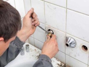 plumber repairing leaking bathtu